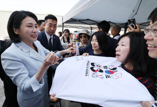 G7 정상회의에 참석하는 이재명 대통령과 함께 캐나다를 방문한 김혜경 여사가 17일(현지시간) 캘거리 한인회관에서 환영나온 주민들의 요청에 티셔츠에 서명하고 있다. 연합뉴스.